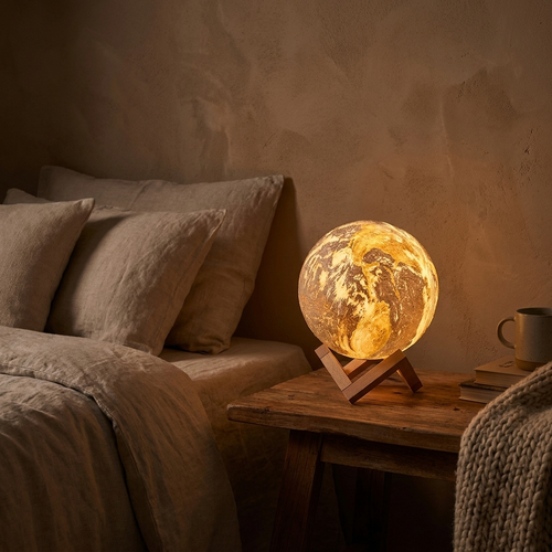 3D printed moon earth globe lamp glowing warm on a bedside table in a cozy bedroom