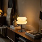 Mid-century glass table lamp with red glass shade glowing in a cozy living room