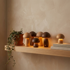 Cluster of wooden mushroom night lights glowing warm amber on an oak shelf in a cozy room