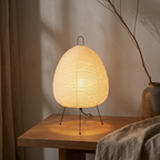 AuraLumen rice paper table lamp glowing warm amber on an oak side table in a Japandi living room at dusk