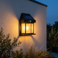 AuraLights solar tungsten wall lamp glowing warm amber on a limewash wall at dusk